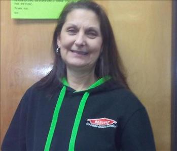 Image of a woman standing in front of a door in SERVPRO apparel.